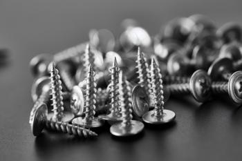 Stack of self-tapping screws, grey background, nobody. Professional instrument, builder equipment, fasteners, fastening tools