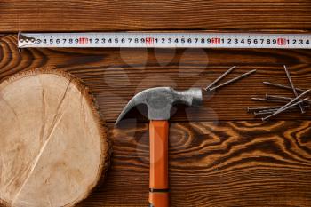 Screw nails, hammer and measuring tape on wooden background, nobody. Professional instrument, carpenter equipment, fasteners, fastening and screwing tools