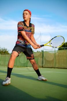 Young male tennis player with racket hits the ball on outdoor court, hitting in action. Active healthy lifestyle, sport game competition, fitness training with racquet