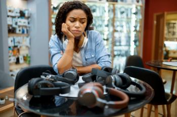 Woman choosing headphones in speaker system store. Female person in audio shop, showcase with earphones on background, buyer in multimedia salon