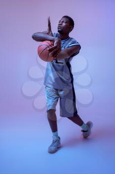 Strong basketball player hand holds ball in studio, neon background. Professional male baller in sportswear playing sport game.