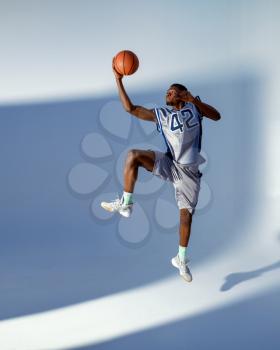 Basketball player with ball shows his skill in studio, high jump in action, neon background. Professional male baller in sportswear playing sport game, tall sportsman