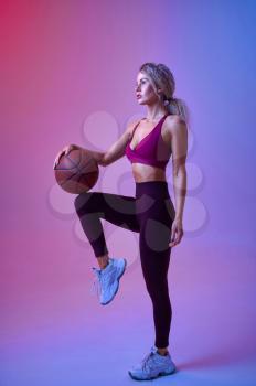 Young sportswoman with ball poses in studio, neon background. Fitness woman at the photo shoot, sport concept, active lifestyle