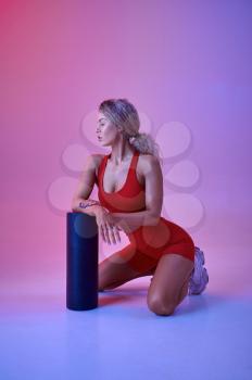 Female athlete in red sportswear in studio, neon background. Fitness sportswoman at the photo shoot, sport concept, active lifestyle motivation