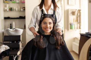 Hairdresser and female customer at the mirror in hairdressing salon. Stylist and client in hairsalon. Beauty business, professional service