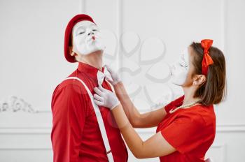 Two mime artists in red costumes look at each other. Pantomime theater, parody comedian, positive emotion, humour performance, funny face mimic and grimace