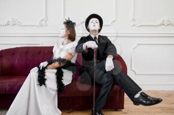 Two mime artists, lady and gentleman sitting on sofa. Pantomime theater, parody comedian, positive emotion, humour performance, funny face mimic and grimace
