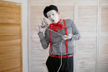 Mime artist with an iron, phone parody, comedy. Pantomime theater, comedian, positive emotion, humour performance, funny face mimic and grimace