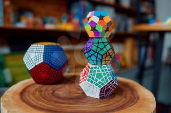 Different puzzle cubes on wooden stump, closeup view, nobody. Toy for brain and logical mind training, creative game, solving of complex problems