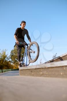 Male bmx biker, jump in action, teenager on training in skatepark. Extreme bicycle sport, dangerous cycle exercise, risk street riding, biking in summer park