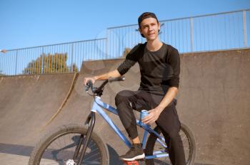 Young male bmx biker leisures on ramp,teenager on training in skatepark. Extreme bicycle sport, dangerous cycle exercise, risk street riding
