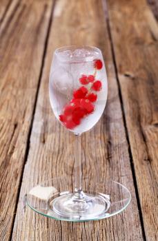 Glass of iced drink with a sprig of red currant
