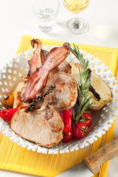 Roasted pork chops and bacon with  potato and red peppers