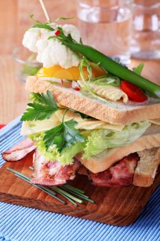 Bacon and cheese sandwich garnished with fresh vegetables