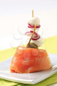 Slice of smoked salmon with baby mozzarella and onion on stick