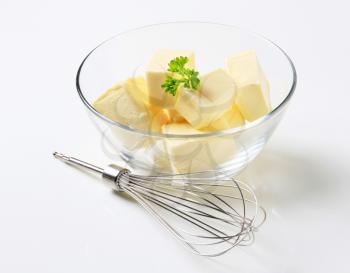 Blocks of fresh butter in a bowl and metal whisk