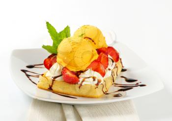 Belgian waffle topped with whipped cream, fresh strawberries and ice-cream