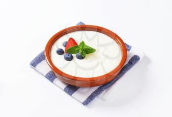 Smooth semolina porridge served in terracotta dish with fresh fruit