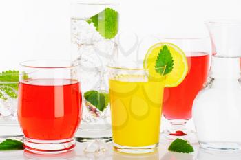 Glasses of water and fruit juices with mint and ice