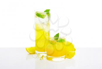 Glasses of lemon juice drink 
  on white background