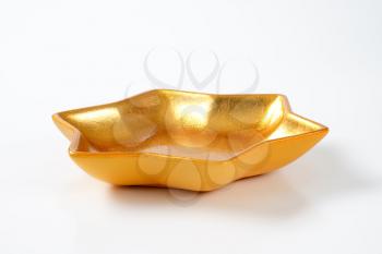 empty star shaped gold bowl on off-white background