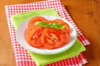 sliced tomato with basil on white plate