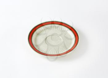 White saucer with red band on the rim