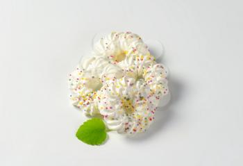 Four wreath-shaped meringue cookies topped with sprinkles