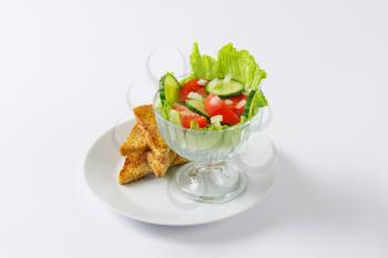 bowl of mixed vegetable salad and slices of toasted bread on white plate
