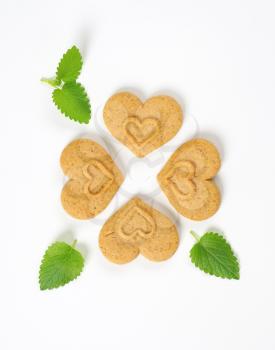 four heart-shaped cookies and mint on white background