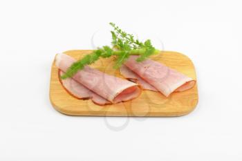 two ham slices with dill on wooden cutting board