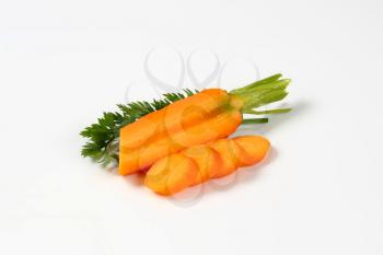 sliced fresh carrots with leaves on white background