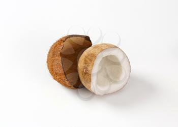 half of fresh coconut and husk on white background
