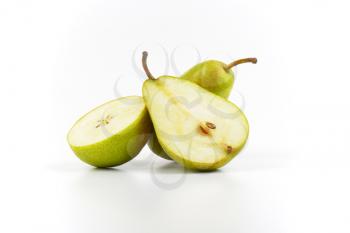 whole and halved ripe pears on white background