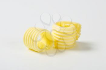 two fresh butter curls on white background
