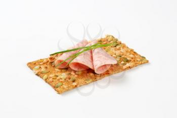 pumpkin seed cracker with thin slices of soft sausage