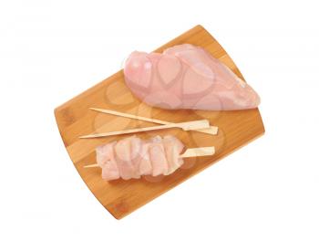raw chicken breast fillet and wooden skewers on cutting board