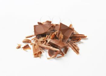 Milk chocolate shavings and pieces on white background