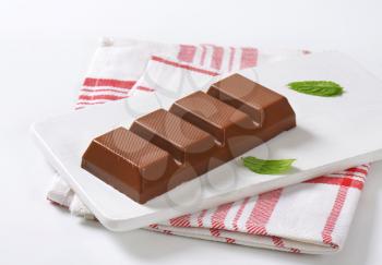 bar of milk chocolate on white wooden cutting board