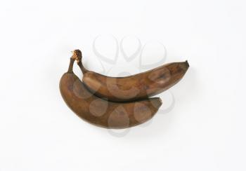 two brown overripe bananas on white background