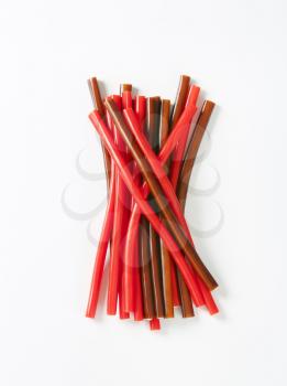 strawberry and cola fondant-filled candy sticks on white background