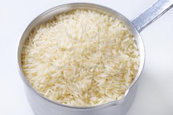 saucepan of uncooked rice on white background - close up