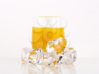 glass of orange juice and ice cubes on white background