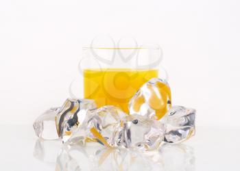 glass of orange juice and ice cubes on white background