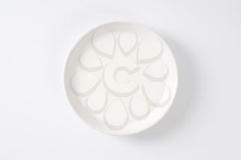 plate of fresh milk on off-white background with shadows