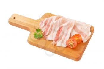 Thin slices of fresh streaky bacon on cutting board