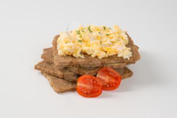 slices of fitness bread with scrambled eggs on white background