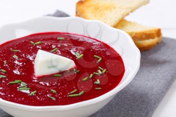 plate of beetroot cream soup with toast on grey place mat - close up