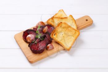 baked beetroot and garlic with toasted bread on wooden cutting board