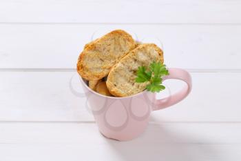 cup of crispy rusks on white wooden background